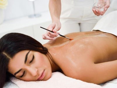 Woman receiving back massage treatment with oil brush in spa wel Arab woman receiving back massage treatment with oil brush in spa wellness center. Beauty and Aesthetic concepts.